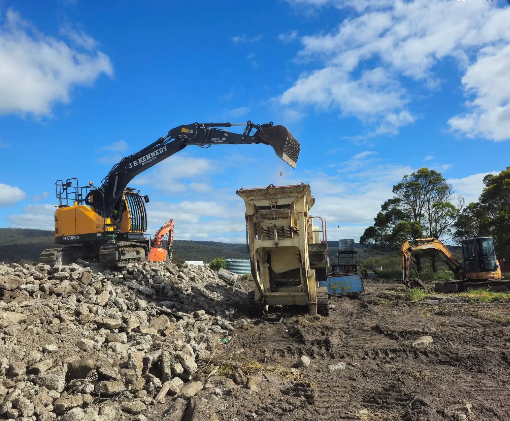 J.R. Kennedy excavator loading a mobile crusher on a demolition site